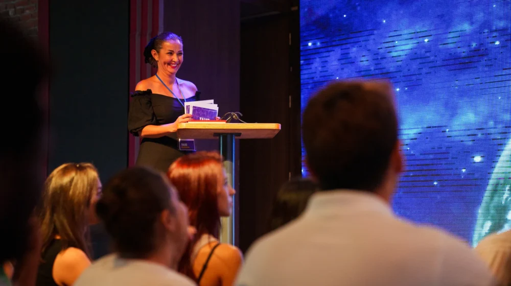 speaker talking on stage and showing presentation to audience